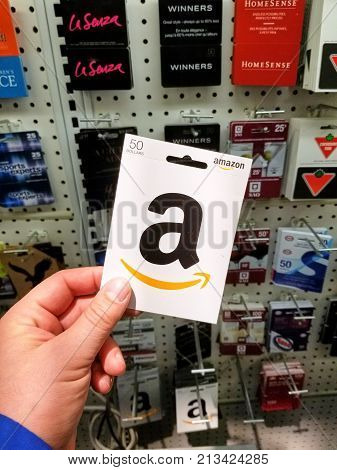 MONTREAL CANADA - NOVEMBER 7 2017: 50 dollar Amazon gift card in a hand on gift cards background. Amazon is an American electronic commerce and cloud computing company based in Seattle Washington