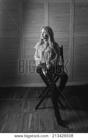 Excited Blonde Sits On A Chair In A Lacy Blouse And Looks At The Light. Long Legs In Latex Pants. Gl