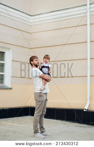 father holds little daughter in her arms on the background of the building 1