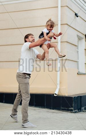 father holds little daughter in her arms on the background of the building 1