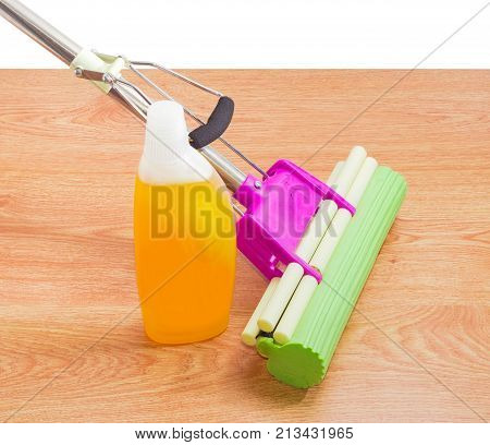 Liquid floor cleaner in plastic bottle and plastic mop with mounting clamp and green sponge on a wooden floor on a white background