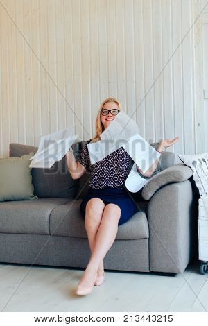 beautiful blond woman with glasses sits on the couch and throws up paper 1