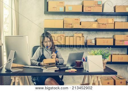 Young asian teenager owner business woman work at home for online shopping checking order and prepaing package the product with office equipment entrepreneur and alpha generation life style concept