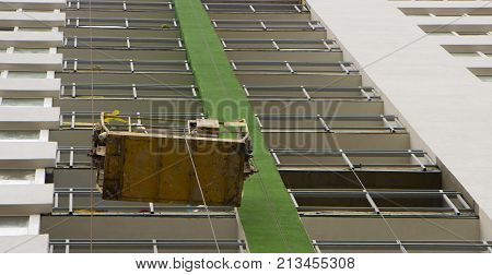basket of fasade installers suspended on the wall of a multi storey building