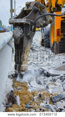 Excavator breaking and drilling the concrete road for repairing close up