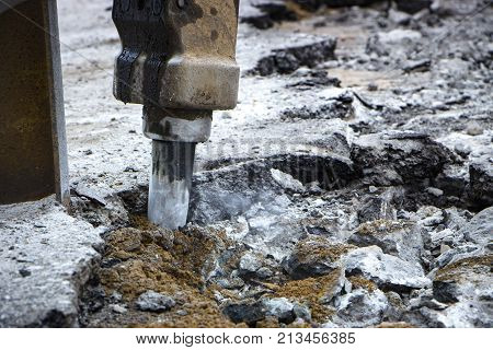 Excavator breaking and drilling the concrete road for repairing close up