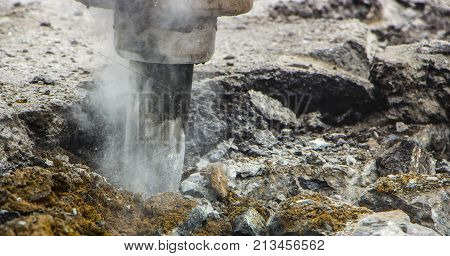 Excavator breaking and drilling the concrete road for repairing close up