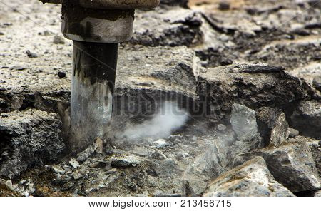 Excavator breaking and drilling the concrete road for repairing close up