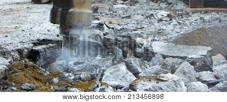 Excavator breaking and drilling the concrete road for repairing close up
