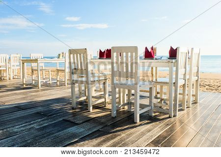 Chanthaburi Thailand - November 18 2016 : Many white wooden chairs with table set on the wooden floor at Chaolao Tosang beach for background or texture.