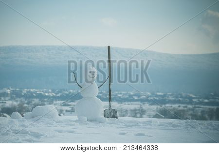New year snowman from snow with shovel. Christmas or xmas decoration. Snowman builder in winter. Happy holiday and celebration. Building and repair work.