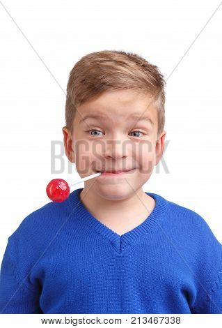 Boy happy in a blue sweater holds a lollipop in his mouth behind a wand on a white isolated background