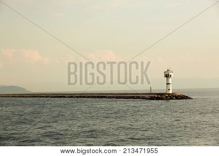 Beautiful seascape with lighthouse. Calm sea and a lighthouse on the pier. Small beacon in the endless sea. Landscape and beacon. Lighthouse.