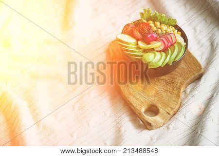 Girl in white jeans holds in hands fork, vegan breakfast meal in bowl with avocado, quinoa, cucumber, radish, salad, lemon, cherry tomatoes, chickpea, chia seeds. Top view, copy space. Clean eating.