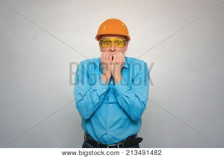 Fearful builder worker covers his mouth with his hands and in shocked from from what happened. Accident in production or construction. Stress situation.