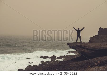 Man on a cliff in a storm.