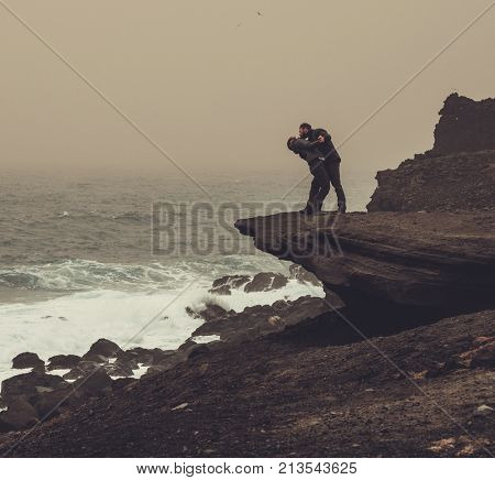 Couple standing on a cliff in a storm.