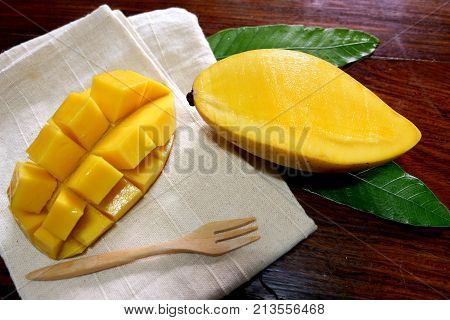 Sweet mango with wooden fork in white napkin on wood table
