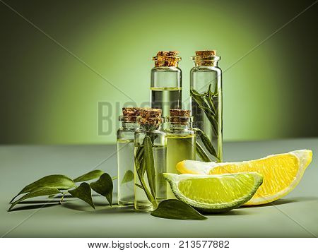 The lime and lemon oil on green studio background on table