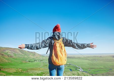 back view of woman traveler with small orange backpack on a walk in the Valley of the river of Hveragerdi Iceland. Hiking Tour of Reykjadalur Hot Springs