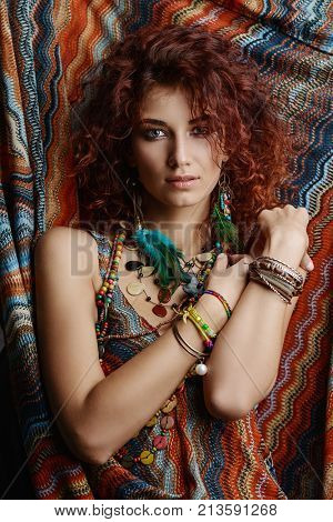 Beautiful bright woman with curly foxy hair wears a dress and beads in boho style. Ethnic style in clothes.