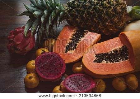 Juicy exotic fruits close up. Pineapple, papaya, mango, gragon fruit on table ready to eat