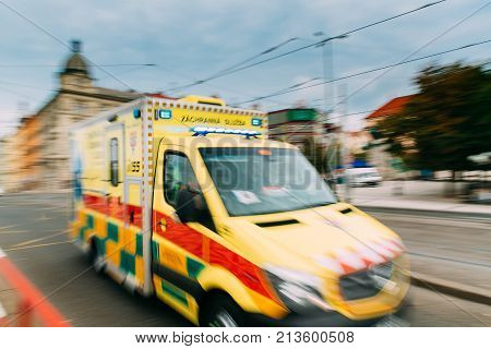 Prague, Czech Republic. Moving With Siren Bright Yellow Emergency Ambulance Reanimation Van Car On Street. Ambulance Car In Blurred Motion Background