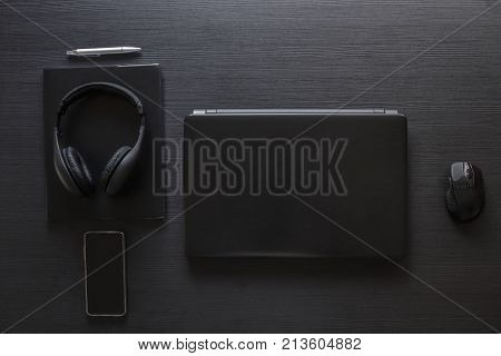 business design tech workspace . laptop , smartphone, headphones , mouse , pen up on a wood background . black