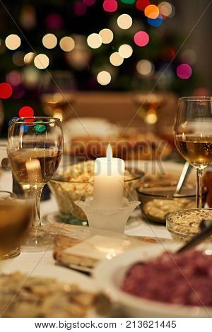 Dining table full of a variety of delicious festive food and wine with a Christmas tree in the background
