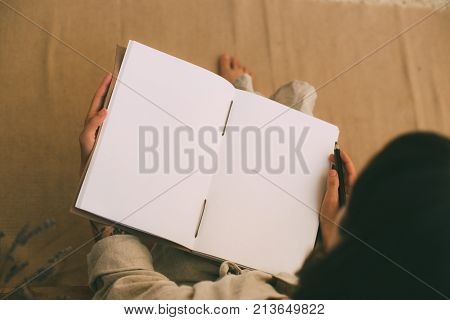 Over head shot of woman holding open wide blank white empty notebook with clean mockup sheets concept diary or new beginning