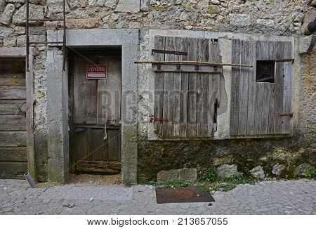A disused building in hill village of Erto in Friuli Venezia Giulia north east Italy. The village is famous locally for having being evacuated following the 1963 Vajont Dam disaster. The sign on the door indicates that the building is for sale