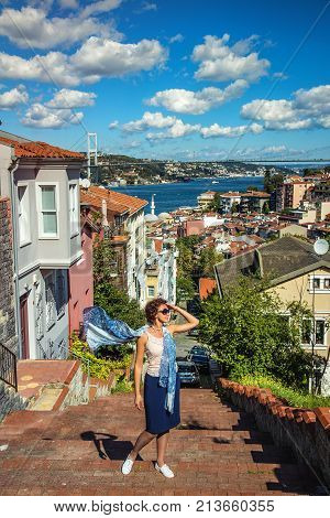 ISTANBUL TURKEY: Beautiful girl standing on a stair in Kuzguncuk district with view of Bosphorus and Bosphorus Bridge on background on October 10 2017