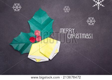Chalk Merry Christmas text with origami bells on a black board school background