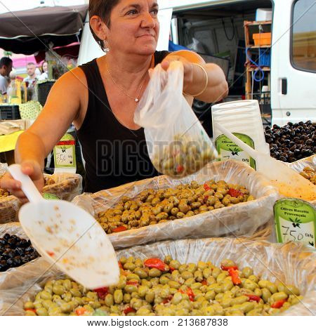 Valras-plage, Herault, France - Aug 25 2017: Woman Serving Olives In A Bag At An Open Air Market In