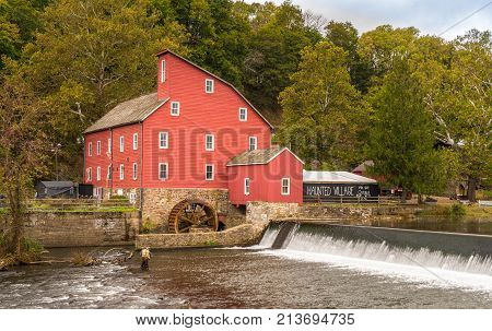 The historic Red Mill in Clinton NJ with people fishing in the river. The village also decorated for halloween as photo taken in Mid October