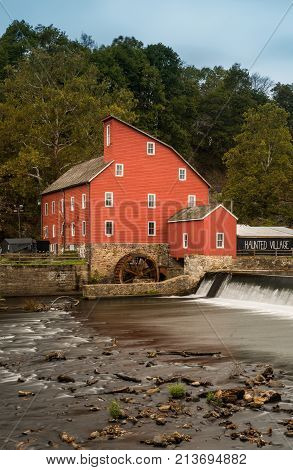 The historic Red Mill in Clinton NJ with people fishing in the river. The village also decorated for halloween as photo taken in Mid October