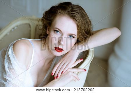 Fashionable female portrait of cute lady in white robe indoors. Close up beautiful sexy model girl in elegant pose. Closeup beauty brunette woman with hairstyle and makeup. Glamorous face with make up