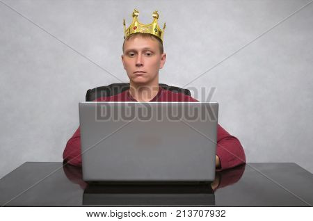 VIP client. Premium user. Success. Smiling happy Business man with golden crown above his head working with laptop computer. Top manager. Smug boss.