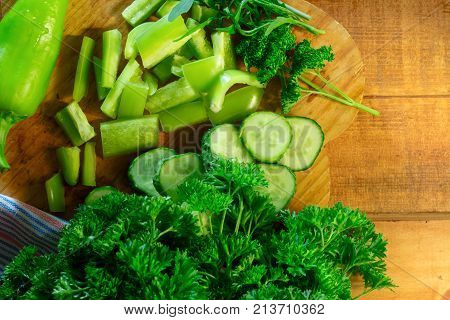 Sliced peppers, cucumbers with parsley and argula on rustic wooden table
