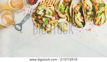 Healthy corn tortillas with grilled chicken, avocado, fresh salsa, limes and beer in glasses over light grey marble table background, top view, copy space. Gluten-free, allergy-friendly food concept