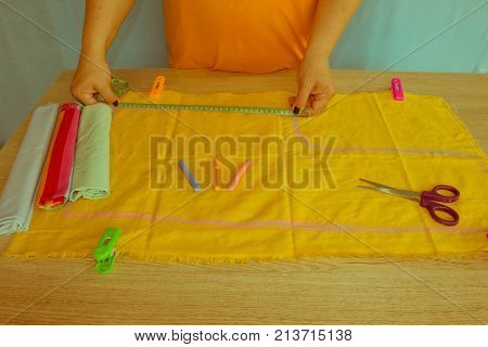 Close up of woman's hand Makes out a pattern from a yellow piece of clothes. Concept of self made clothes - Retro color