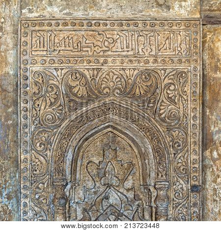 Ornate engraved stone wall with floral patterns and calligraphy at Ibn Tulun Mosque Cairo Egypt
