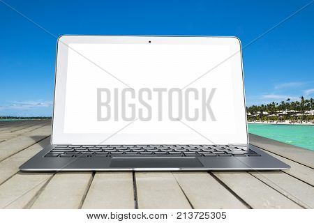 Laptop computer on wooden table. Top ocean view. Tropical island background. Open blank laptop computer empty space. Front view with copy space. Isolated white screen