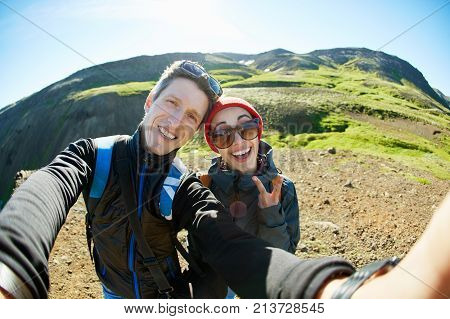 couple hikers travelers on a walk in the Valley of the river of Hveragerdi Iceland. Hiking Tour of Reykjadalur Hot Springs. woman and man making selfie in Iceland