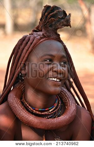 KAMANJAB NAMIBIA - FEB 1 2016: Young unidentified Himba woman with the typical necklace and hairstyle shown in himba tribe village