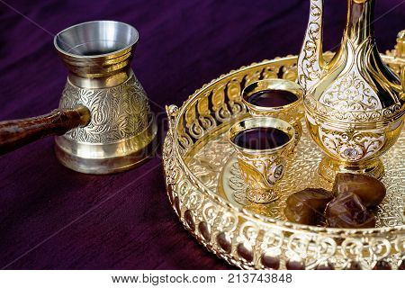 Still life Golden Traditional Arabic coffee set with dallah coffee pot (jezva) cup and dates. Dark background. Selective focus.