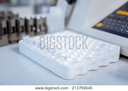 Ready for use. Shiny small test tube standing in the special case which putted on the table with other medical equipment surrounding it in the lab