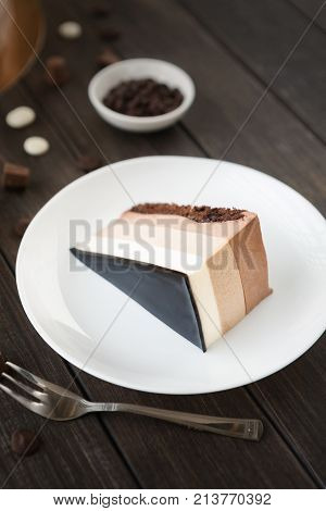Triple chocolate mousse cake covered with mirror glaze, with chips. Contemporary food art, delicious pigeon's milk dessert, copy space