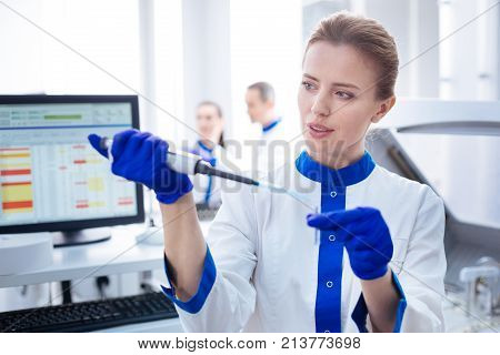 Great job.  Smart concentrated female laboratorian receiving negative results standing in front of the computer and  looking at the medical  appliance