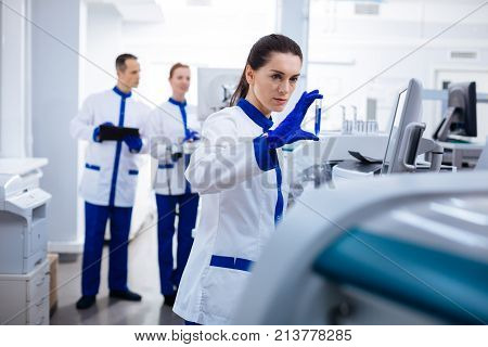 Fascinating discovery. Pleasant concentrated female researcher  studying sample when holding test tube and posing in the lab